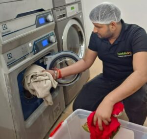 Man near laundry machine holds red clothes